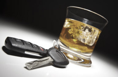 A close-up image of a glass of whiskey with ice cubes next to a set of car keys on a reflective surface, evoking the consequences highlighted in DUI testing.