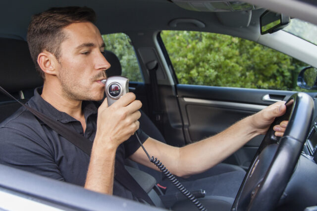 Man blowing into breathalyzer IID; First Offense DWI Attorney concept image