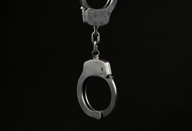 Locked police handcuffs on a black background with text / writing