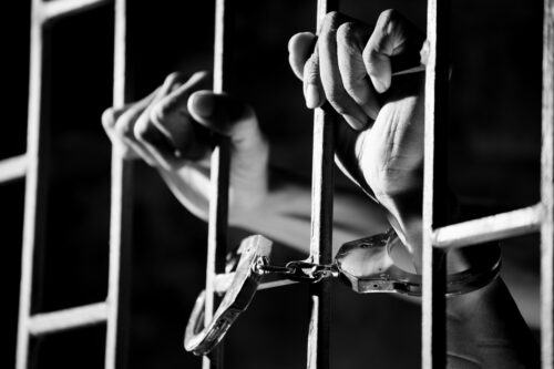 handcuffs person behind bars