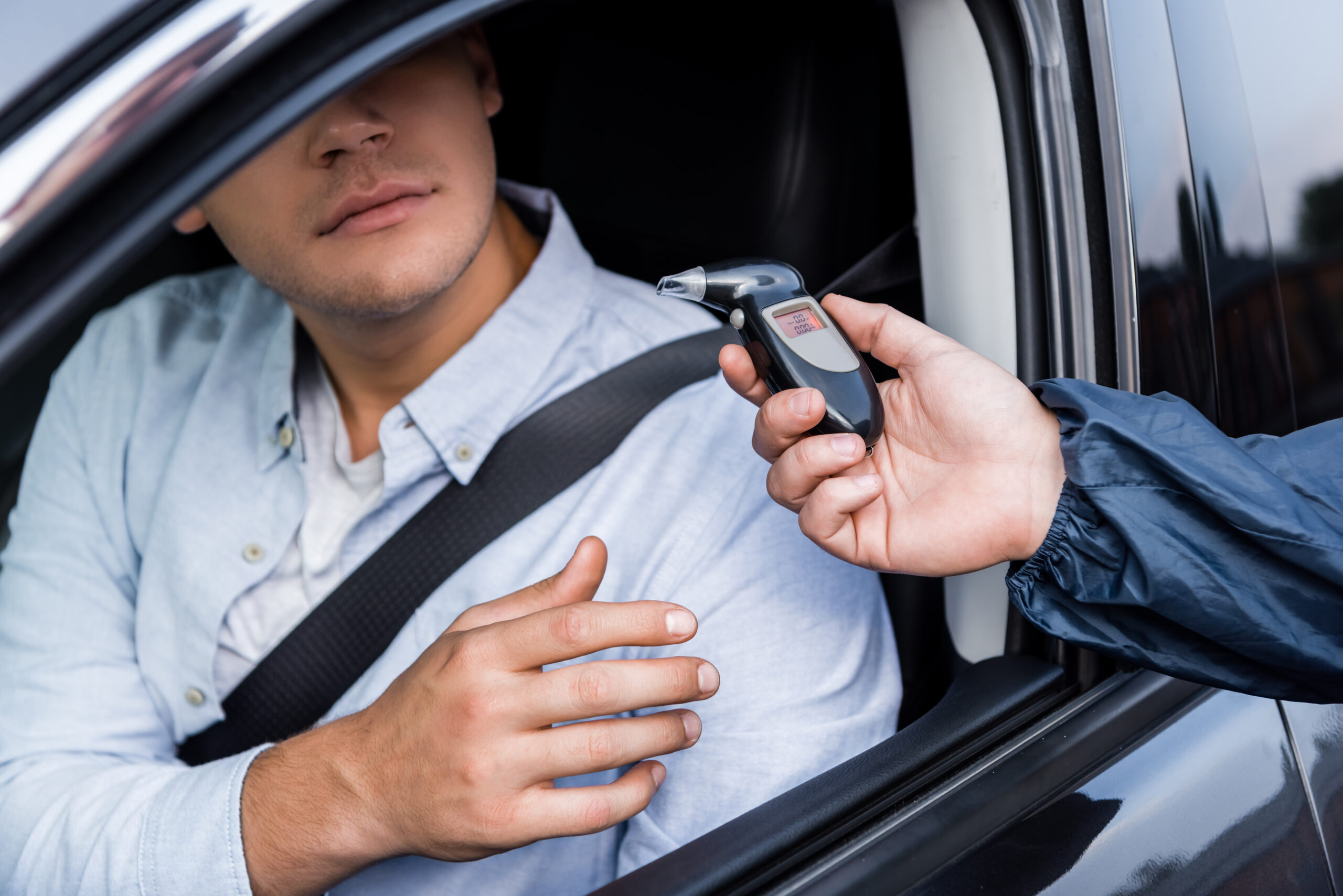 cropped view of driver taking breathalyzer from policeman while sitting in car