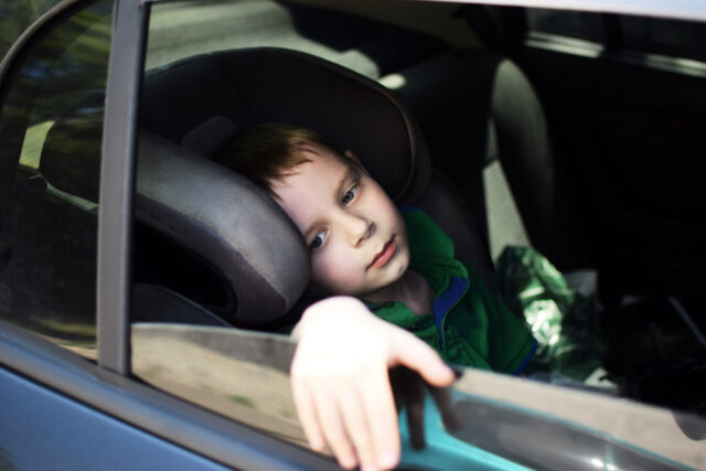sad child in car with hand out of the window
