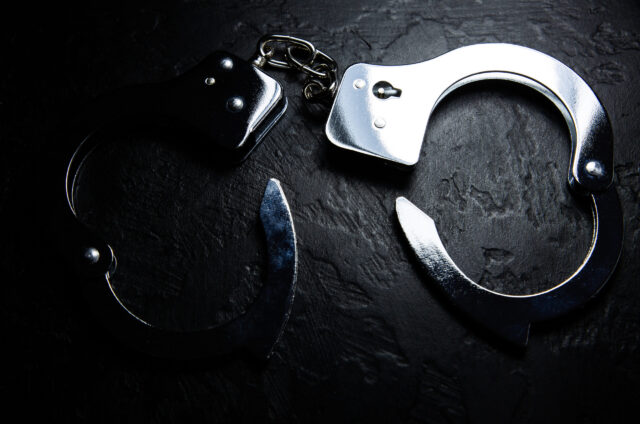 Police metal real handcuffs on the black background. Crime and robbery, prison concept.