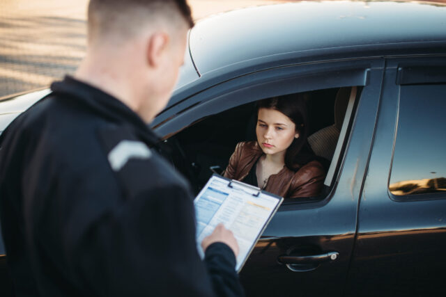 Policeman in uniform writes a fine to female driver. Law protection, car traffic inspector, safety control job.